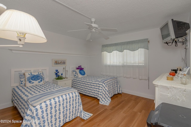 bedroom featuring ceiling fan, hardwood / wood-style floors, and a textured ceiling