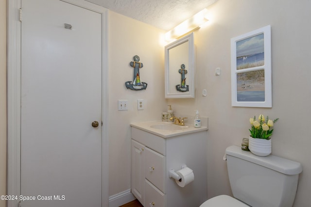 half bathroom with toilet, a textured ceiling, and vanity