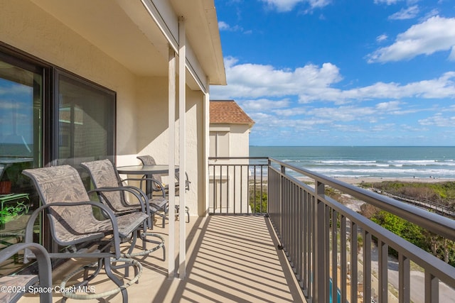 balcony featuring a view of the beach and a water view