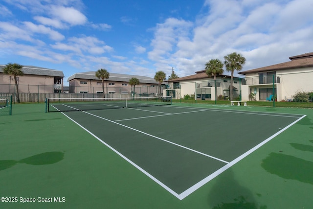 view of tennis court featuring fence and a residential view