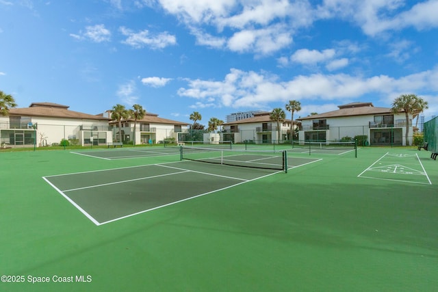 view of tennis court with fence and a residential view