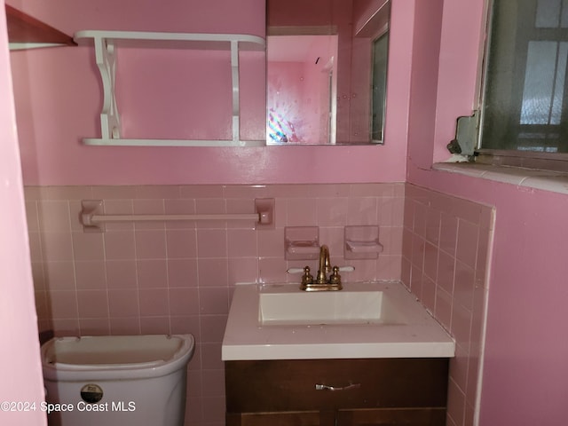 bathroom with vanity, toilet, and tile walls