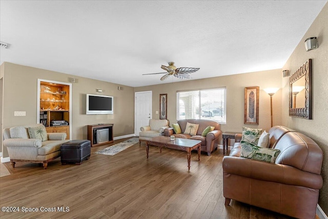 living room featuring hardwood / wood-style floors, ceiling fan, and built in shelves