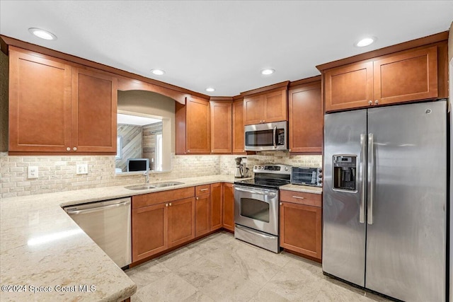 kitchen featuring backsplash, stainless steel appliances, light stone counters, and sink