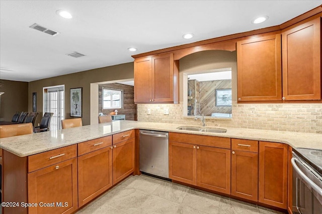 kitchen featuring kitchen peninsula, light stone countertops, tasteful backsplash, stainless steel appliances, and sink