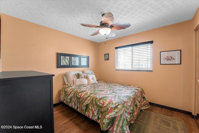 bedroom with hardwood / wood-style flooring, ceiling fan, and a textured ceiling