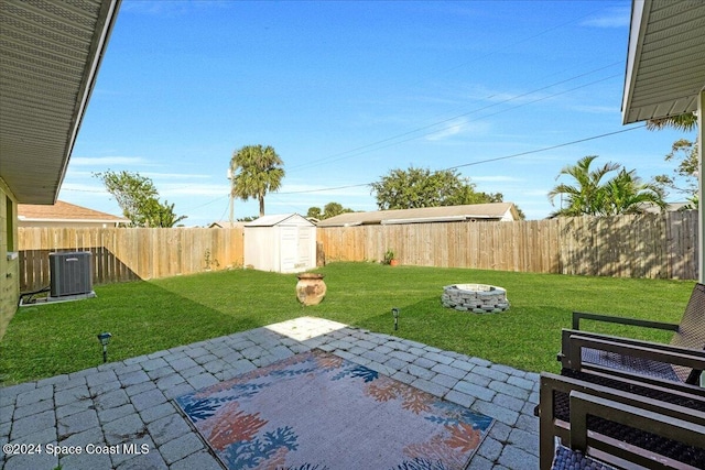 view of yard featuring a storage shed, a fire pit, central AC unit, and a patio area