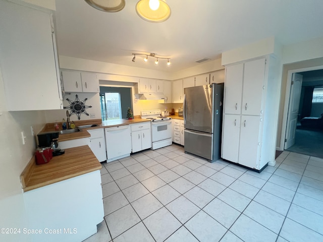 kitchen with light tile patterned floors, white appliances, white cabinetry, and sink