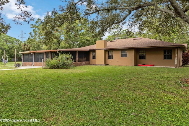 rear view of house featuring a lawn and a sunroom