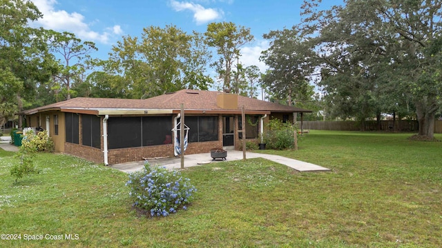 back of property with a lawn, a patio area, and a sunroom