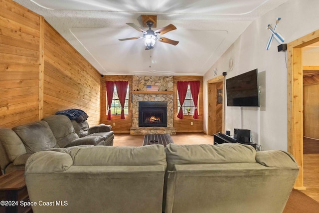 living room with lofted ceiling, wooden walls, ceiling fan, light wood-type flooring, and a fireplace