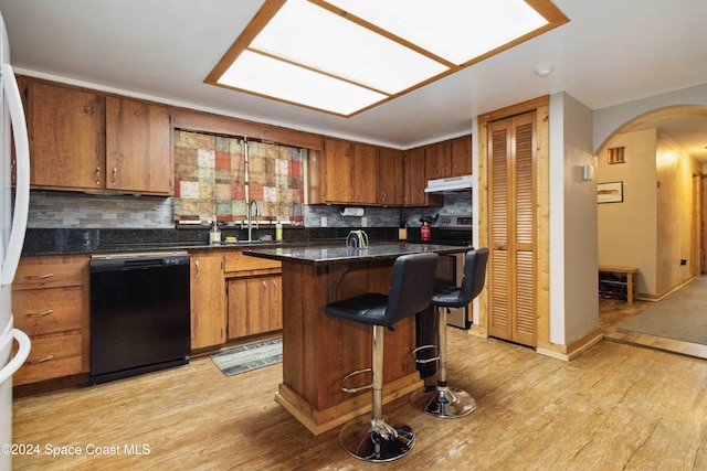 kitchen featuring dishwasher, tasteful backsplash, light hardwood / wood-style flooring, a breakfast bar, and a kitchen island