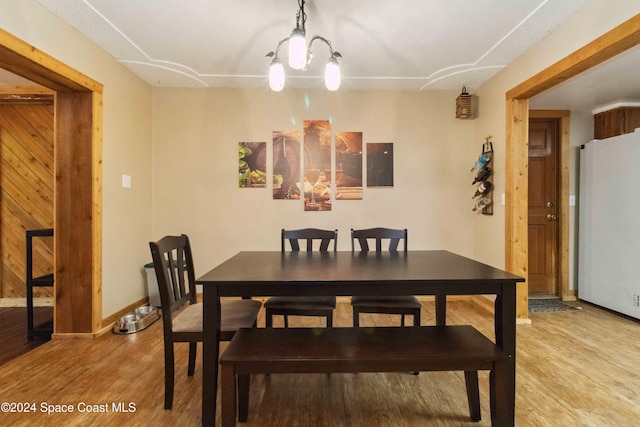 dining room with an inviting chandelier, electric panel, and light hardwood / wood-style flooring