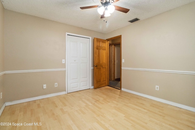 unfurnished bedroom featuring ceiling fan, light hardwood / wood-style floors, and a textured ceiling