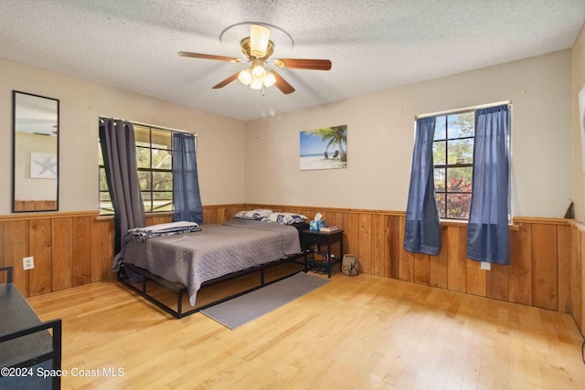 bedroom featuring multiple windows, ceiling fan, light hardwood / wood-style flooring, and a textured ceiling