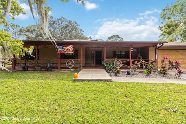 back of property featuring ceiling fan and a yard