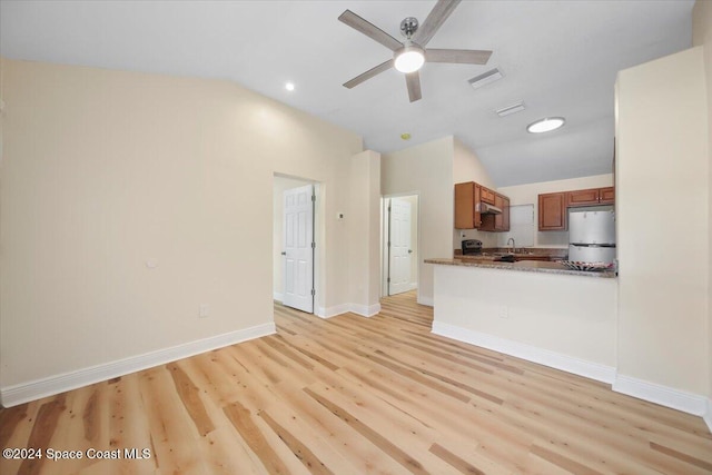 kitchen with refrigerator, light hardwood / wood-style floors, kitchen peninsula, and vaulted ceiling