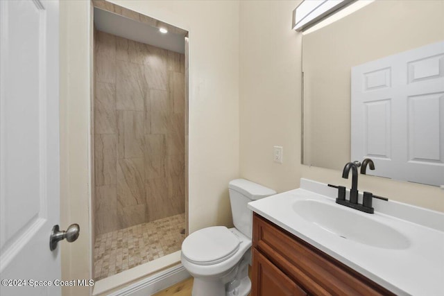 bathroom with toilet, vanity, and tiled shower