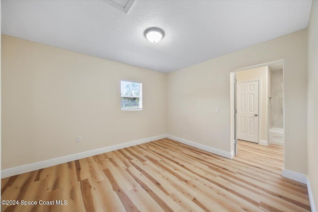 spare room with light hardwood / wood-style floors and a textured ceiling