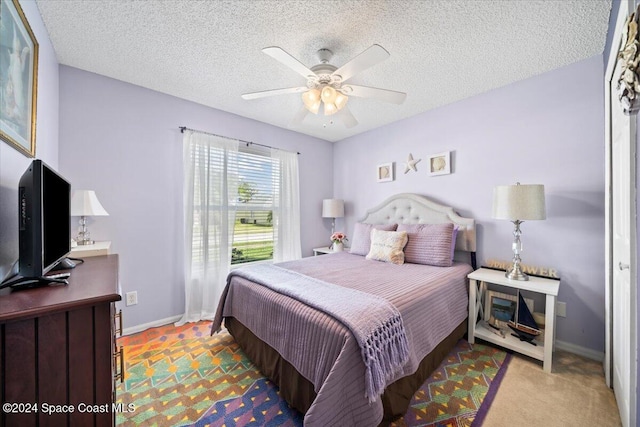 bedroom with a textured ceiling, ceiling fan, and light carpet