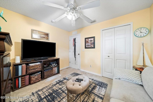 carpeted living room featuring ceiling fan and a textured ceiling