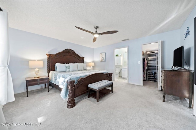 bedroom with a walk in closet, ensuite bath, light colored carpet, ceiling fan, and a closet