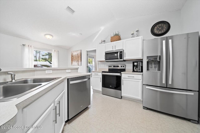 kitchen featuring white cabinets, a textured ceiling, stainless steel appliances, and lofted ceiling