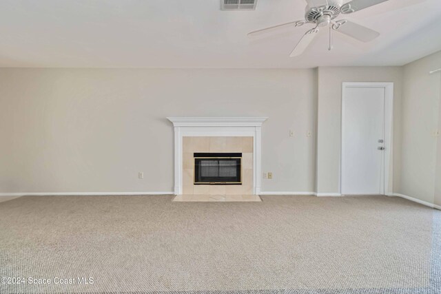 unfurnished living room featuring ceiling fan, carpet floors, and a tiled fireplace