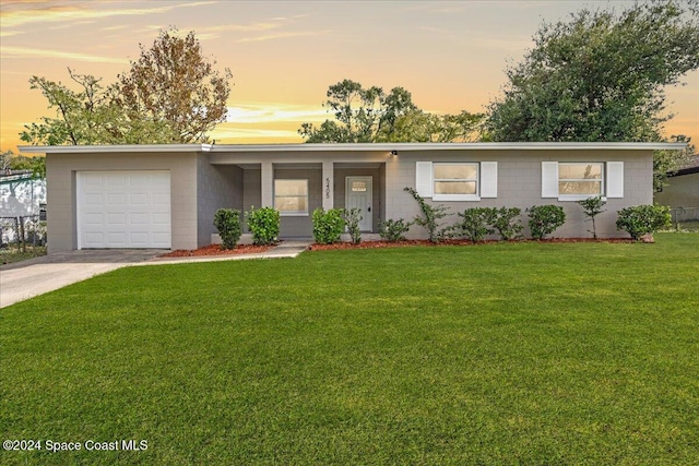 single story home with a garage and a yard