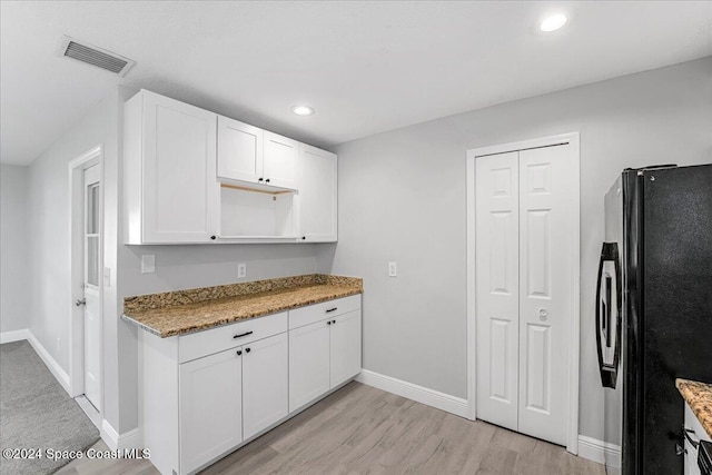 kitchen featuring white cabinets, stainless steel fridge, light stone countertops, and light hardwood / wood-style floors