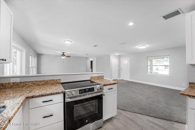 kitchen featuring white cabinetry, light hardwood / wood-style flooring, light stone counters, and stainless steel range with electric stovetop