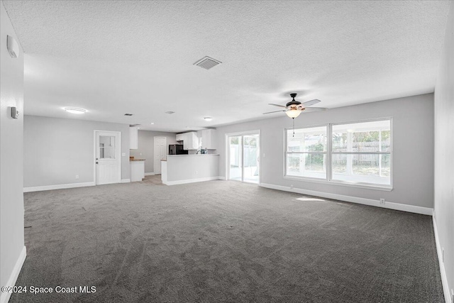 unfurnished living room with carpet flooring, a textured ceiling, and ceiling fan