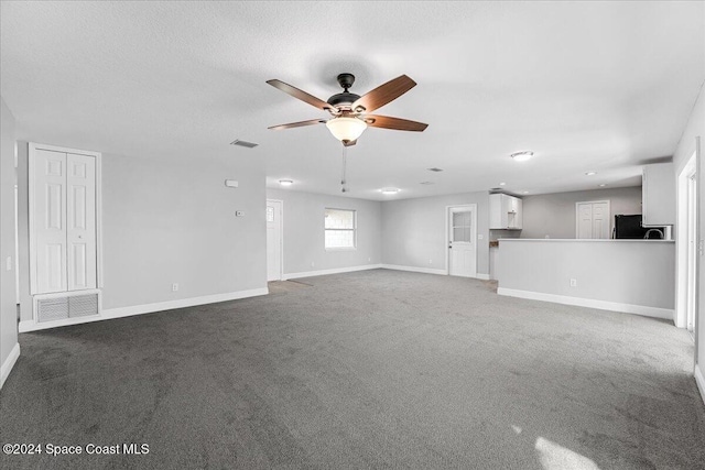 unfurnished living room with carpet flooring, ceiling fan, and a textured ceiling