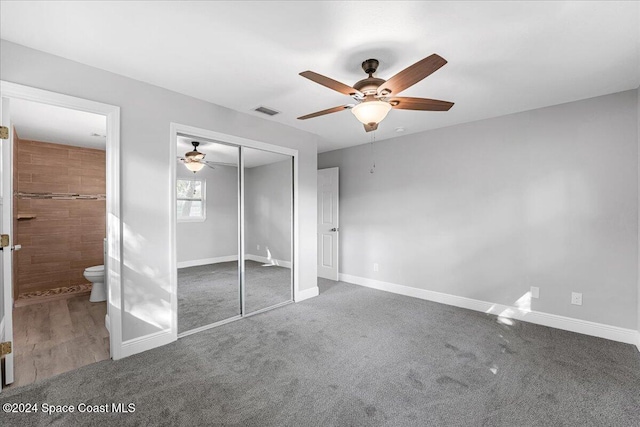 unfurnished bedroom featuring carpet flooring, ensuite bath, ceiling fan, and a closet