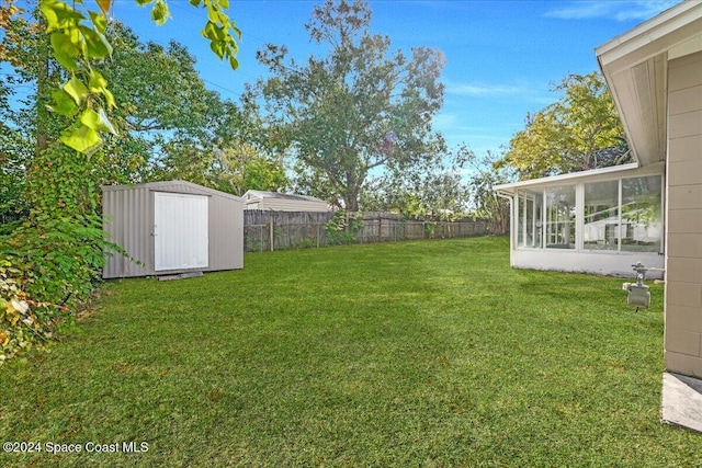 view of yard featuring a sunroom and a storage unit