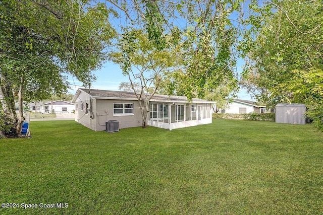 back of house featuring a lawn, a sunroom, cooling unit, and a storage shed