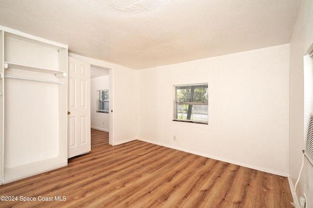 unfurnished bedroom featuring hardwood / wood-style floors, a textured ceiling, and a closet