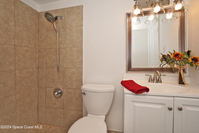 bathroom featuring a tile shower, vanity, and toilet