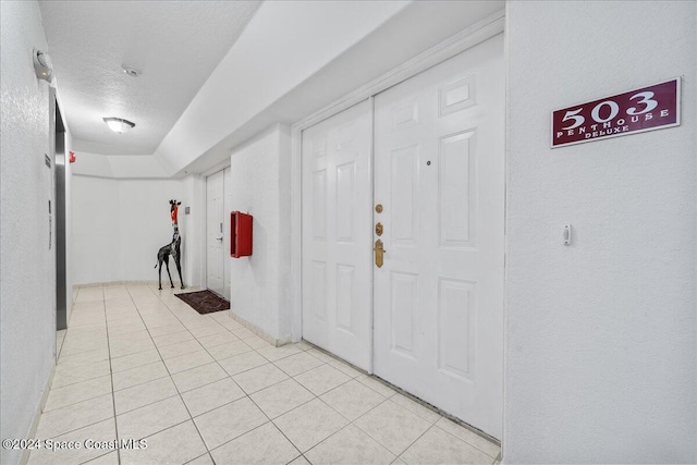 hall featuring a textured ceiling and light tile patterned flooring