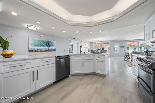 kitchen featuring kitchen peninsula, appliances with stainless steel finishes, sink, white cabinets, and a chandelier