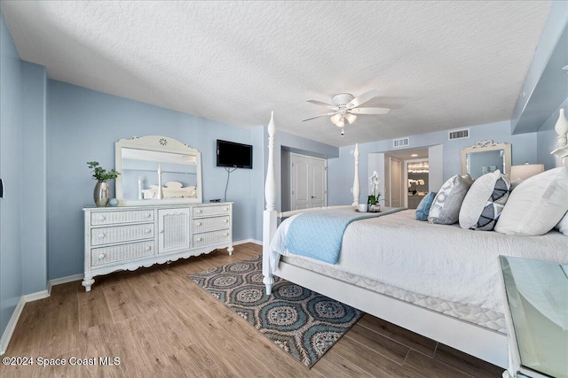 bedroom with a textured ceiling, a closet, hardwood / wood-style flooring, and ceiling fan