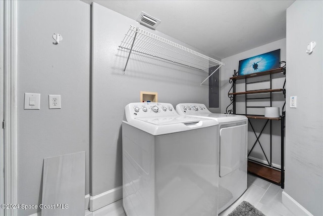 clothes washing area with washing machine and dryer and light tile patterned floors