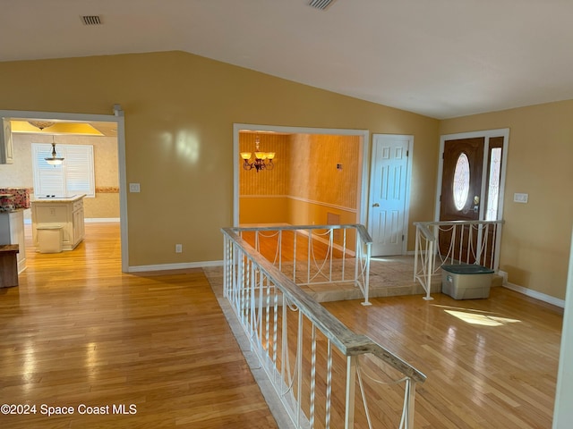 foyer entrance with light wood-type flooring, lofted ceiling, and a notable chandelier