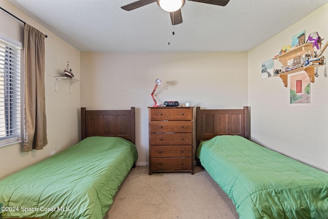 carpeted bedroom featuring ceiling fan and a textured ceiling