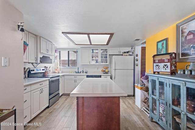 kitchen with white cabinets, white refrigerator, stainless steel range with electric cooktop, and light hardwood / wood-style flooring