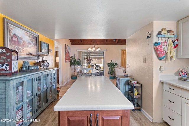 kitchen with white cabinetry, a center island, light hardwood / wood-style floors, and an inviting chandelier