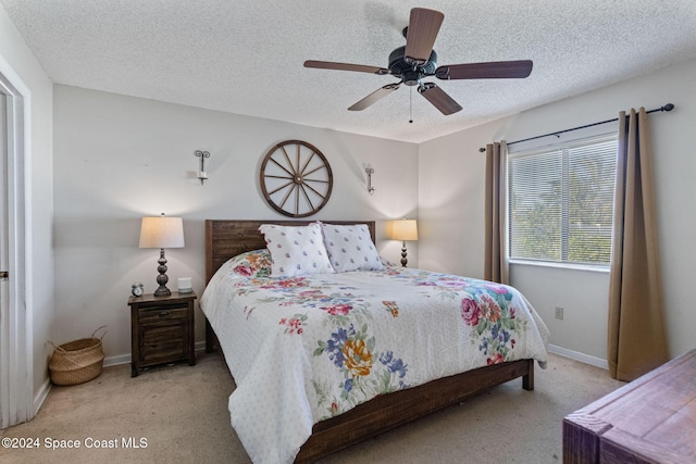 carpeted bedroom featuring ceiling fan and a textured ceiling