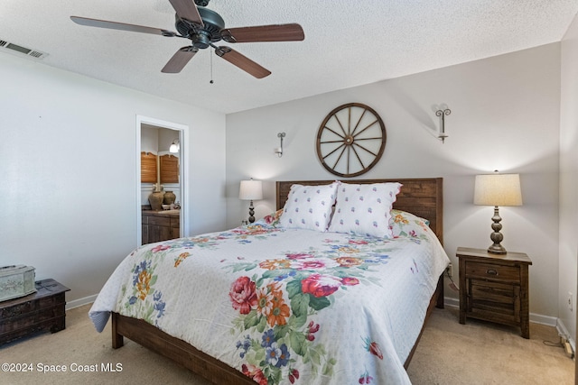 bedroom with a textured ceiling, light colored carpet, ceiling fan, and ensuite bathroom