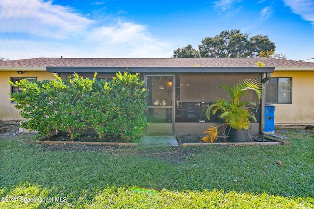 rear view of property featuring a sunroom and a yard