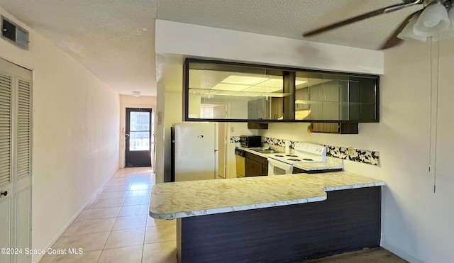 kitchen with white electric range oven, kitchen peninsula, stainless steel fridge, a textured ceiling, and light tile patterned flooring